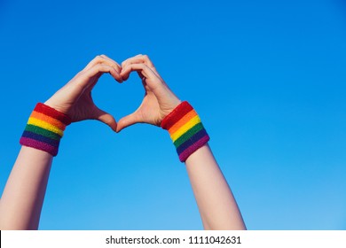 Gay Pride Concept. Hand Making A Heart Sign With Gay Pride LGBT Rainbow Flag Wristband