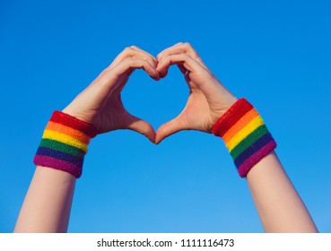 Gay Pride Concept. Hand Making A Heart Sign With Gay Pride LGBT Rainbow Flag Wristband