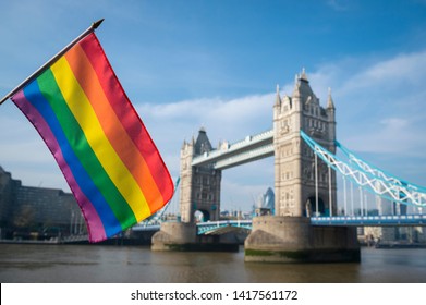 Gay Pride Rainbow Flag Hanging In Front Of The London Skyline At Tower Bridge On A Bright Sunny Summer Day Along The River Thames