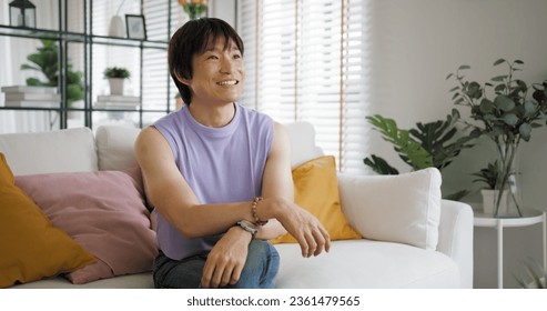 Gay queer asian man non-binary influencer sitting easy at home sofa. Asia non binary LGBT young guy adult two people happy relax smile talking asking advice face to face in mental health care therapy. - Powered by Shutterstock