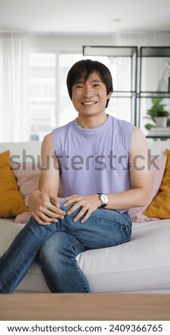 Gay queer asian man non-binary influencer sitting easy at home sofa. Asia people non binary LGBT young adult guy happy relax talking sharing advice in mental health self care webcam looking at camera.