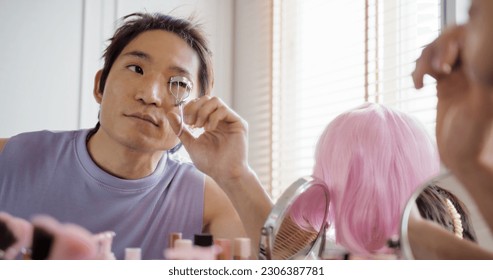 Gay queer man non-binary beauty blogger makeup artist at home cross dressing up apply face skin care eye make up brush. Real asia LGBT young guy adult people happy relax smile looking at mirror pride. - Powered by Shutterstock