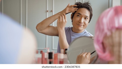 Gay queer man non-binary beauty blogger makeup artist at home cross dressing up apply face skin care eye make up brush. Real asia LGBT young guy adult people happy relax smile looking at mirror pride. - Powered by Shutterstock