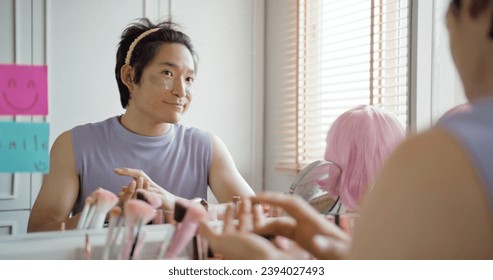 Gay queer man non-binary beauty blogger makeup artist at home cross dressing up apply face skin care eye make up brush. Real asia LGBT young guy adult people happy relax smile looking at mirror pride. - Powered by Shutterstock