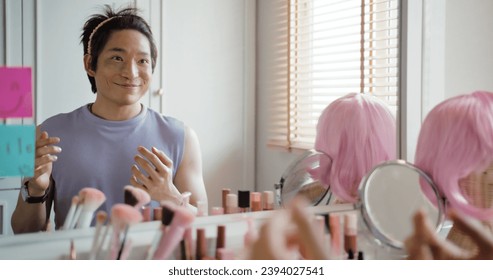 Gay queer man non-binary beauty blogger makeup artist at home cross dressing up apply face skin care eye make up brush. Real asia LGBT young guy adult people happy relax smile looking at mirror pride. - Powered by Shutterstock