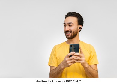 Gay Queer Young Latin Man With Wireless Ear Buds, Looking Away While Smiling. Copy Space White Background