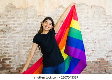 Gay Woman Holding A Rainbow Pride Flag And Laughing While Supporting The LGBT Community Wearing A Black Mock-up T-shirt