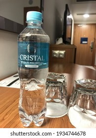 Gdansk, Poland - February 22nd 2021: Close Up Of A Mineral Water Bottle Over A Wooden Desk In A Polish Hotel Room. Two Glasses Stand Besides The Half Litre Plastic Bottle.