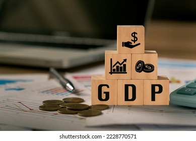 GDP, Gross Domestic Product symbol, word 'GDP' in a wooden block and computer-backed background.  There was a coin placed beside the wooden block.  The concept of gross domestic product, or GDP.