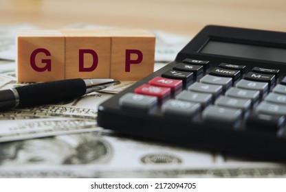 GDP. Symbol of gross domestic product.  Business growth and GDP. Concept of gross domestic product.  GDP on a wooden block with a calculator and a pen on the dollar bill.