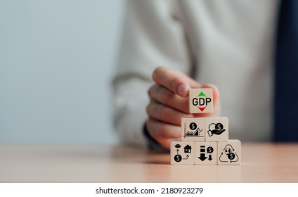GDP, symbol of gross domestic product businessman holding a wooden block with up and down icons the words 'GDP' copy space Business and GDP growth. Gross domestic product concept.