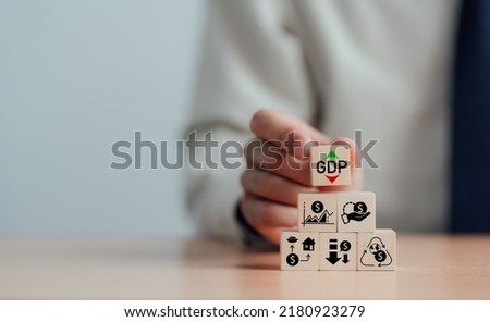GDP, symbol of gross domestic product businessman holding a wooden block with up and down icons the words 'GDP' copy space Business and GDP growth. Gross domestic product concept.