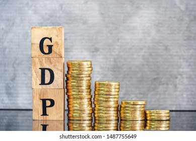 GDP Text On Wood Cube And Gold Coins Stack Shape Volume Down Side , Finance And Economic Concept. 