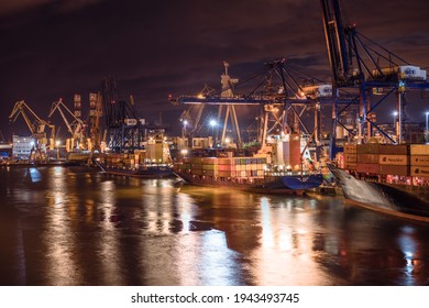 Gdynia, Poland - 09.01.2017: Ship Loading Cranes Working With Heavy Containers In The Port Of Gdynia, Poland. Loading Big Cargo Ships At Night. Harbour Lights And Heavy Machinery.