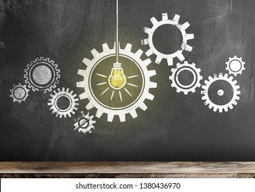 gear with interlocking cogwheels with glowing light bulb on blackboard, teamwork concept
