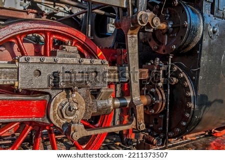 The gearbox with red painted wheel, piston and linkage of an old steam locomotive