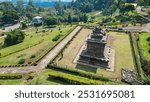 
The Gedong Songo Temple complex rests on a hillside, surrounded by misty green mountains. The ancient stone temples are scattered across the landscape, offering breathtaking views and a serene,  