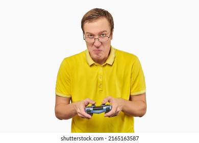 Geek gamer nerd in glasses and yellow T-shirt with gamepad isolated on white background. Young adult nerd guy holding joystick and playing videogames on TV, excited video game player