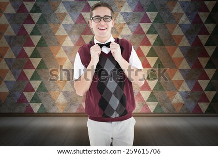 Geeky hipster fixing his bow tie against orange background with vignette