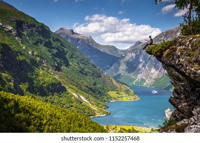 Geiranger - July 30, 2018: Traveler at Flydalsjuvet viewpoint looking down at the stunning UNESCO Geiranger fjord, Norway - Shutterstock ID 1152257468