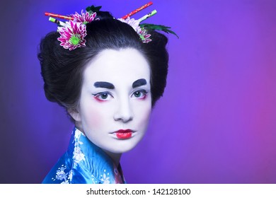 Geisha. Young woman in blue kimono and with flowers in her hair.