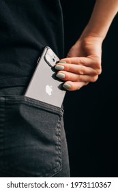 Gelendzhik, Russia, 24 March 2021: The woman dressed in black clothes get out an iPhone 11 out of her back pocket. A close-up of the Apple logo.