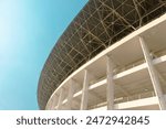 Gelora Bung Karno stadium curved facade against bright blue sky, GBK is multi purpose stadium venue for sports event, concert, or political rally in Jakarta - Indonesia.