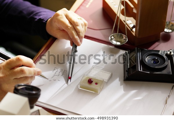 gemstone appraisal  - a gemologist examines a
ruby using tweezers and evaluating gemstones - closeup view of gem
specialists hands while at
work