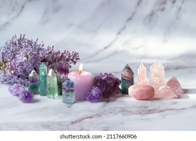 unscharfer abstrakter Marmorhintergrund mit Kristallen, Kerzen und Lila-Blumen, Nahaufnahme. flache Tiefe. künstlerischer Geräuschfilter. weicher selektiver Fokus