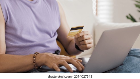 Gen Z Gay queer man non-binary pride at home. Asia LGBT young guy adult people happy relax sitting at sofa use omni channel easy buy now pay later BNPL shop store online bank loan. Cash sale discount. - Powered by Shutterstock