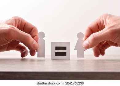 Gender Equality Concept With Hands Catching Cutouts Shaped Like Man And Woman Holding Sign With Equal Sign