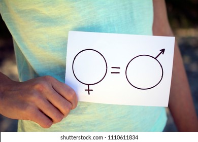 Gender Equality Concept, A Piece Of Paper With A Female And A Male Symbol In A Woman's Hand