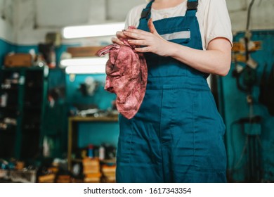 Gender Equality. Woman In Uniform, Working In A Workshop, Which Wipes His Hands With A Rag. Auto Shop In The Background. Close Up