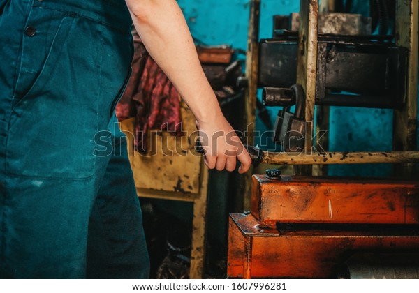 Gender\
equality. A woman in uniform working near the machine, hands\
close-up. In the background, a blue wall and\
tools