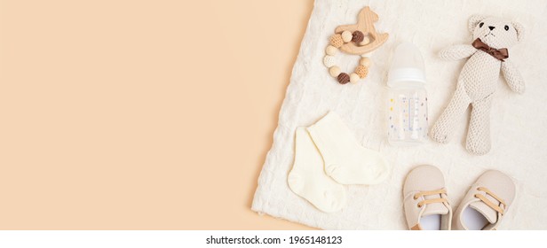 Gender Neutral Baby Shoes And Accessories Over Beige Background.