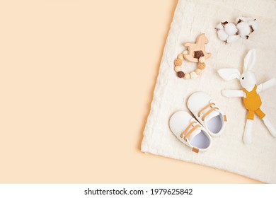 Gender Neutral Baby Shoes And Accessories Over Beige Background.