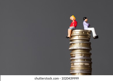 Gender Pay Equality Concept. Man And Woman On A Stack Of Coins.