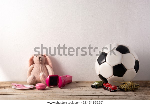 Gender stereotype toys on wooden table and\
white background