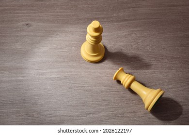 Gender Violence Concept Depicted With Chess King And Queen Piece Lying Down On Wood Table. Elevated View.