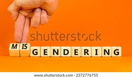 Gendering or misgendering symbol. Concept words Gendering Misgendering on wooden blocks. Beautiful orange table orange background. Psychologist hand. Gendering or misgendering concept. Copy space.