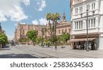 General Archive of the Indies Timelapse hyperlapse in Seville, Spain, housed in the ancient merchants exchange. Tram moving along Avenue de la Constitucion. Blue sky with scattered clouds.