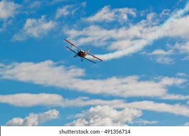 General Aviation Plane Leaves A Trail In A Beautiful Blue Sky With Clouds. Training Flight By Famous Russian AN-2 Aircraft With Bright Livery