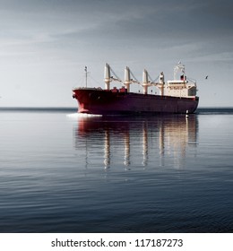 General Cargo Ship With Cranes Sailing In A Still Water. Dramatic Sky, Dark Clouds Before The Storm. Freight Transportation, Nautical Vessel, Global Communications, Industry, Carrying, Logistics