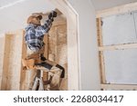 General Construction Contractor Attaching Drywall Using Cordless Drill Driver. Caucasian Remodeling Worker in His 40s.