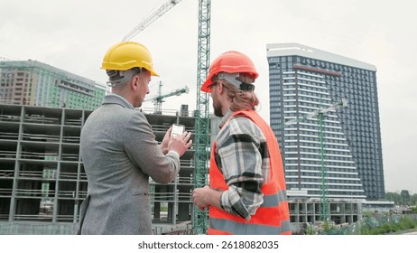 General contractor and subcontractor using smartphone during site inspection