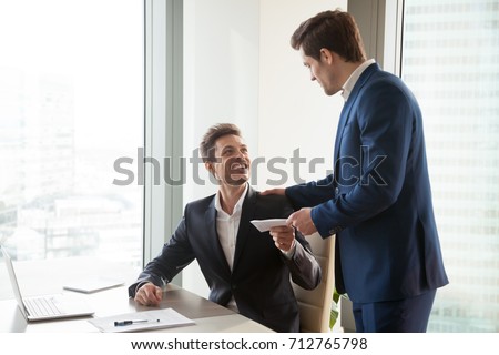 General manager presenting an envelope with premium or bonus cash to male company official. Boss congratulating happy employee with career promotion, thanking for good job and giving financial reward 