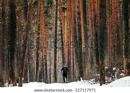 General plan athlete runner running a marathon winter on a snowy trail in pine forest