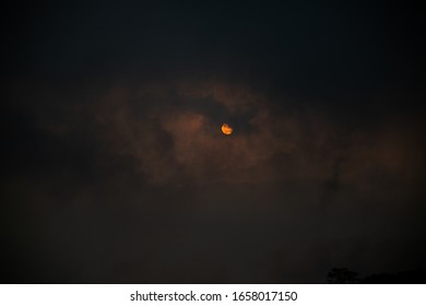 General plane of the sun between the clouds in a sunset that creates a palette of orange, black and variations forming the silhouette of an eye