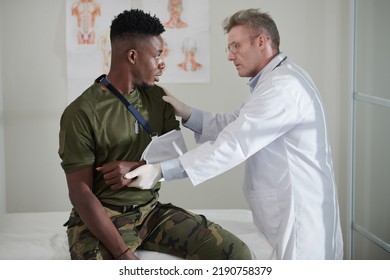 General Practitioner Examining Wounded Soldier With Broken Arm Wearing Shoulder Sling