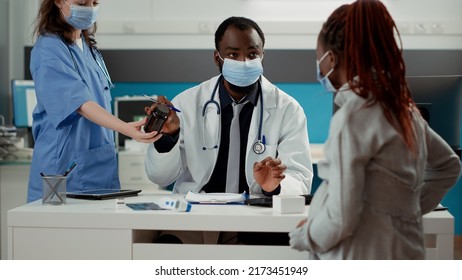 General Practitioner Giving Bottle Of Pills As Prescription Treatment To Woman Expecting Child In Medical Office. Male Obstetrician Attending Appointment With Pregnant Person To Give Medication.